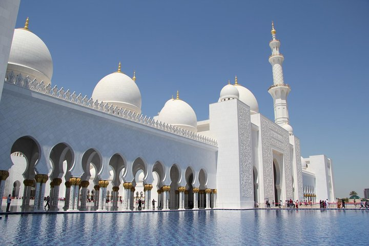 Marvel at the stunning architecture of the Sheikh Zayed Grand Mosque where shimmering reflections dance on tranquil waters inviting you to uncover the rich culture and history of Abu Dhabi.